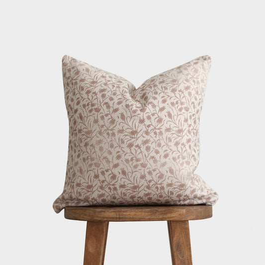 Beige and taupe floral patterned pillow with thick weave fabric on wooden stool.