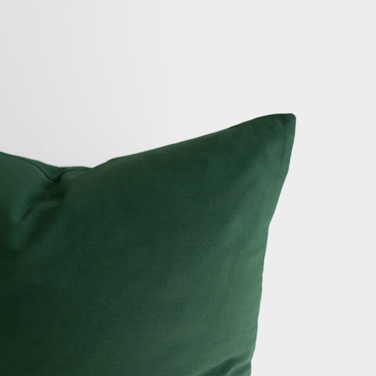 Dark green cushion cover with a corner fold visible against a white background.