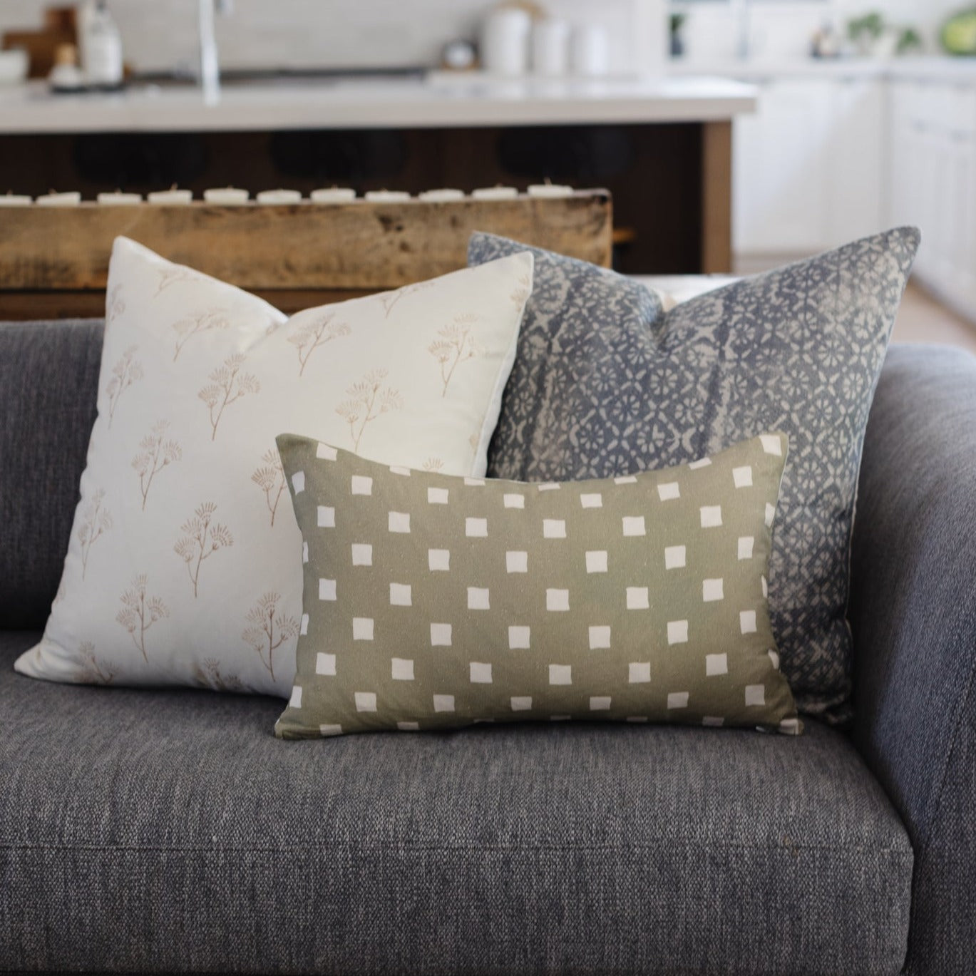 Olive green rectangular pillow with white spaced check pattern displayed on gray sofa.