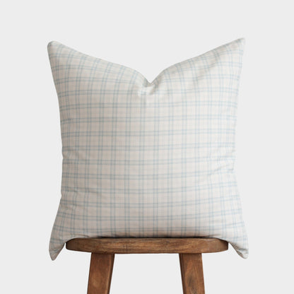 Light blue and beige plaid pillow with pointed corners displayed on a wooden stool.