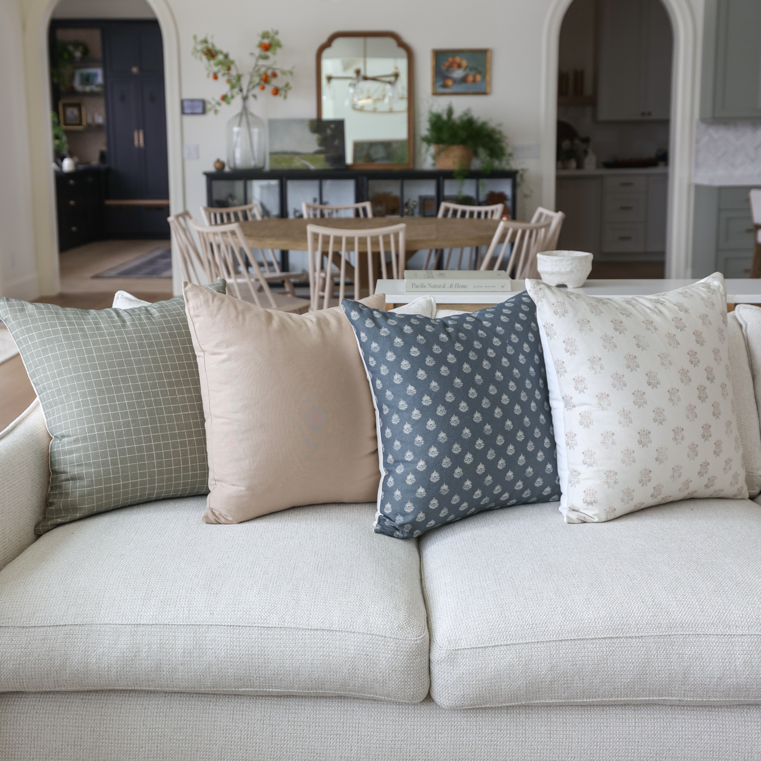 Blue patterned throw pillow with small geometric print displayed on cream sofa with coordinating pillows.