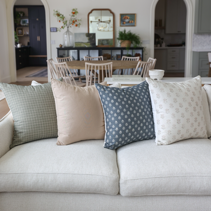 Blue patterned throw pillow with small geometric print displayed on cream sofa with coordinating pillows.