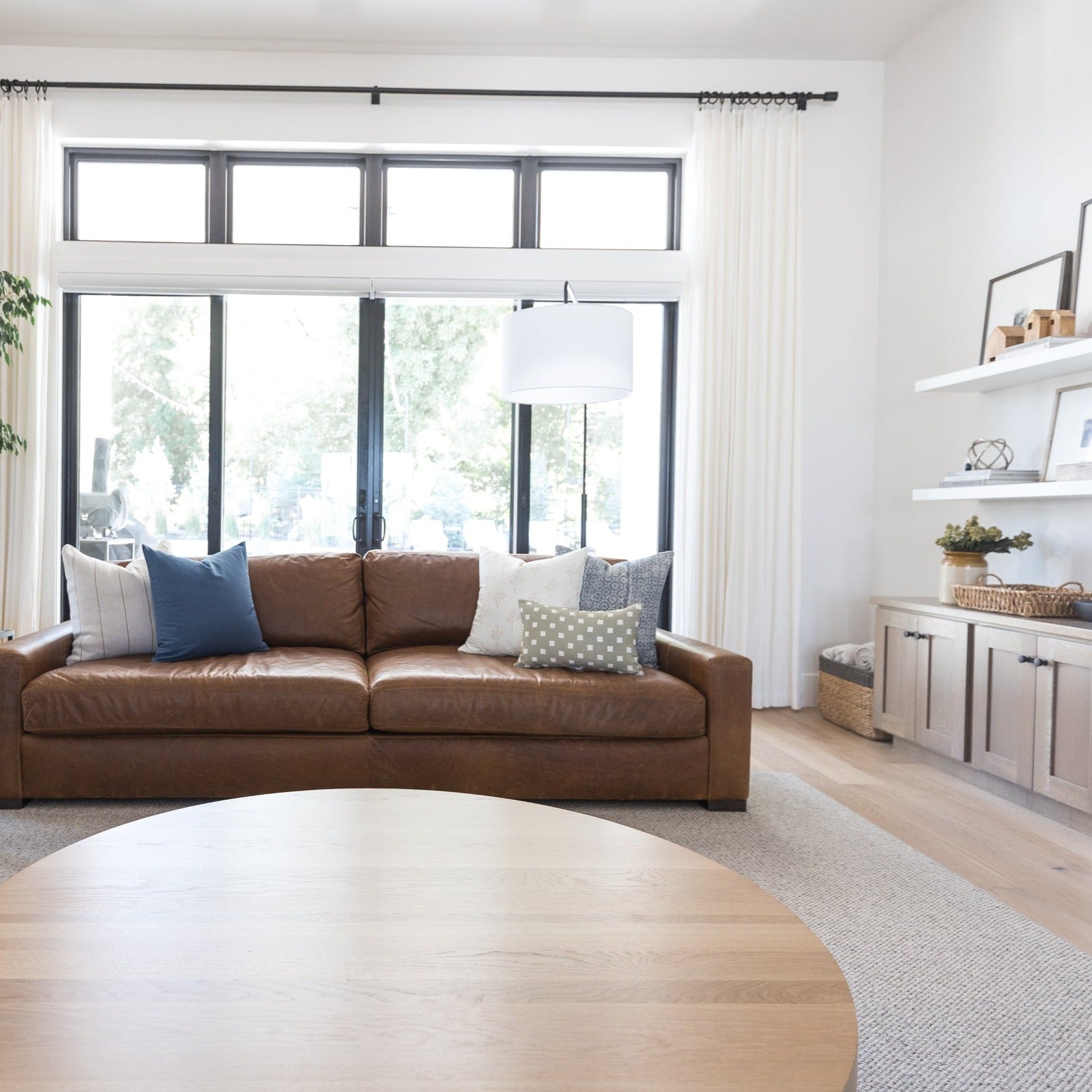 Olive-colored pillow with spaced check pattern displayed on brown leather sofa in living room.