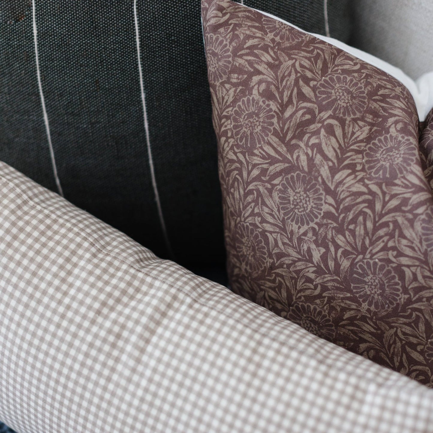 Colette pillow showing mauve floral pattern, black textured fabric, and white gingham check detail in layered arrangement.