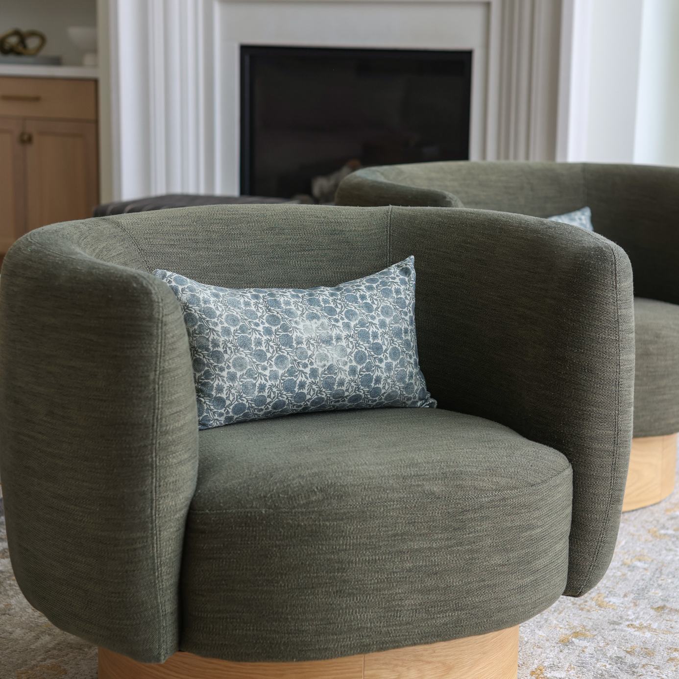 Blue and white patterned lumbar pillow placed on a gray upholstered chair.