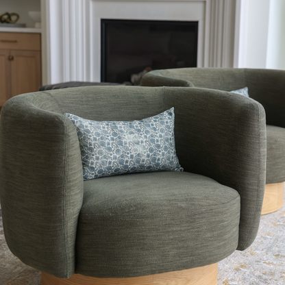 Blue and white patterned lumbar pillow placed on a gray upholstered chair.
