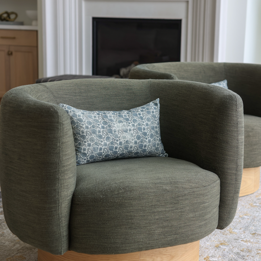Blue and white patterned lumbar pillow placed on a gray upholstered chair.