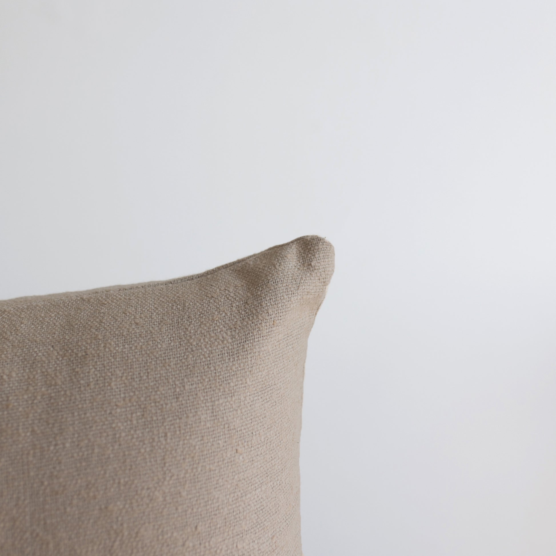 Beige boucle textured pillow with soft, looped fabric surface and rounded corner detail.