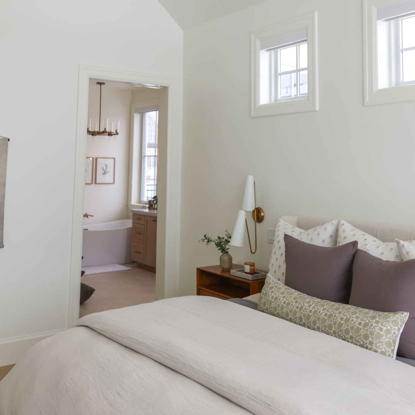 Green and cream patterned lumbar pillow displayed on a bed with other pillows and bedding.