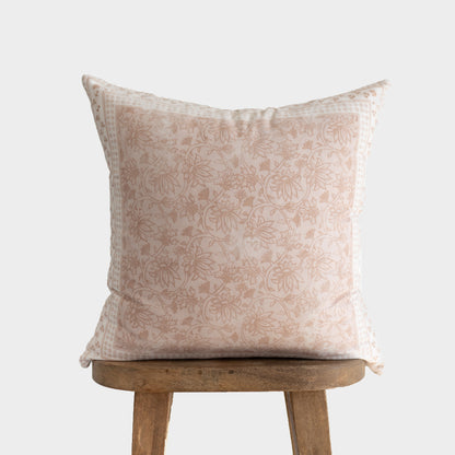 Cream and tan floral patterned throw pillow displayed on a wooden stool.