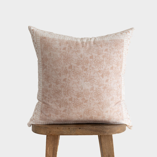 Cream and tan floral patterned throw pillow displayed on a wooden stool.