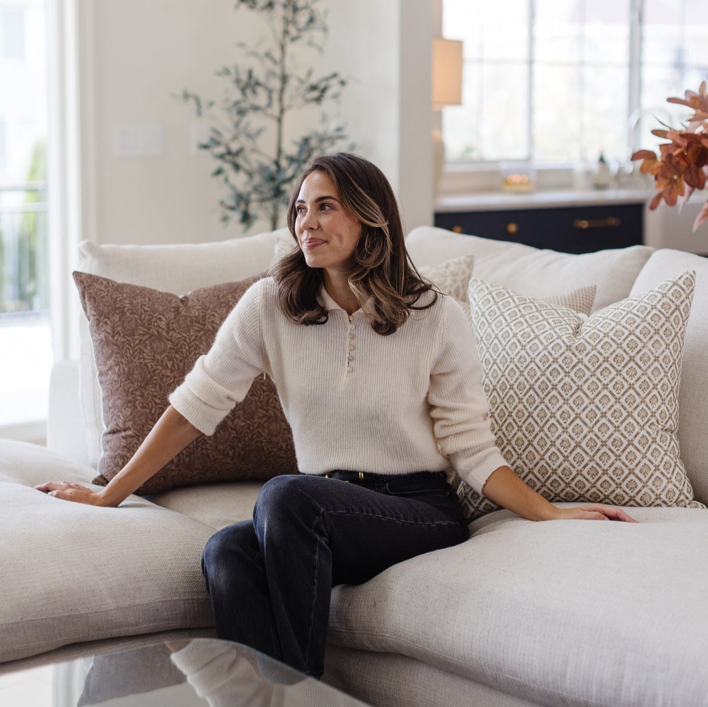 Four decorative pillows in neutral tones with geometric and textured patterns arranged on a cream sofa.