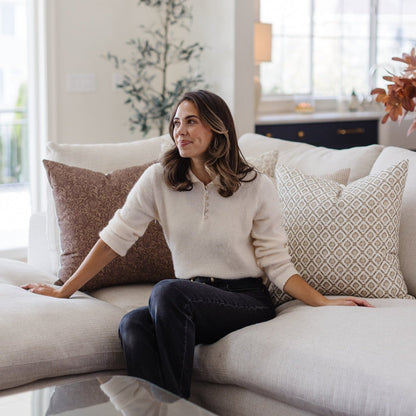 Four decorative pillows in neutral tones with geometric and textured patterns arranged on a cream sofa.