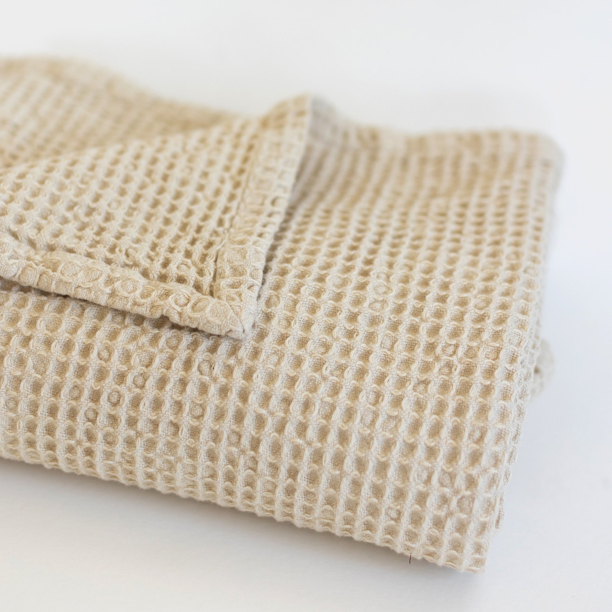 Ivory waffle-textured blanket folded with visible grid pattern weave.