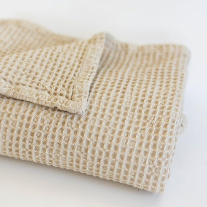 Ivory waffle-textured blanket folded with visible grid pattern weave.