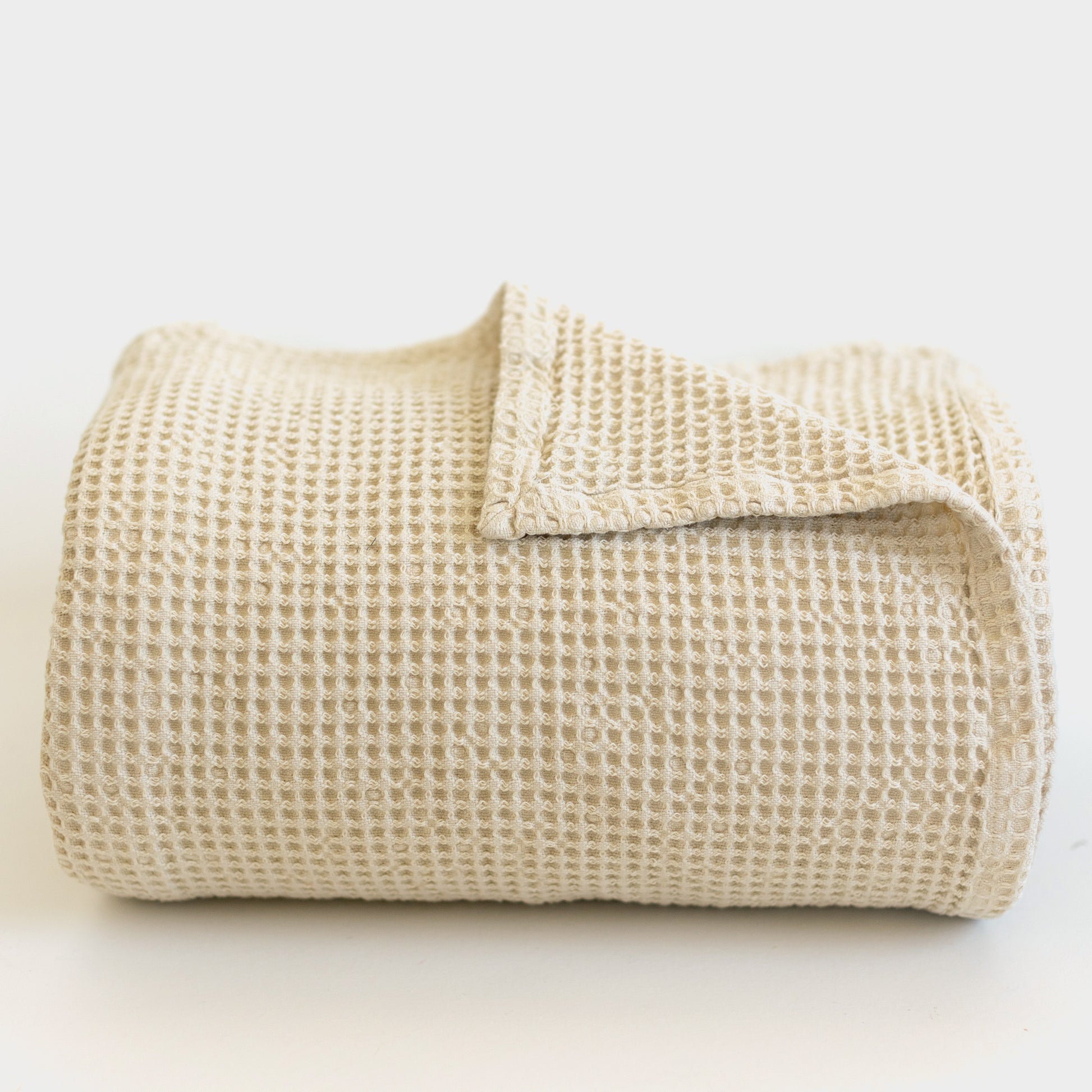 Ivory waffle-textured blanket folded and displayed against a white background.