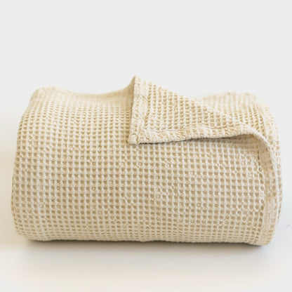 Ivory waffle-textured blanket folded and displayed against a white background.