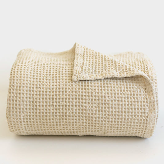 Ivory waffle-textured blanket folded and displayed against a white background.