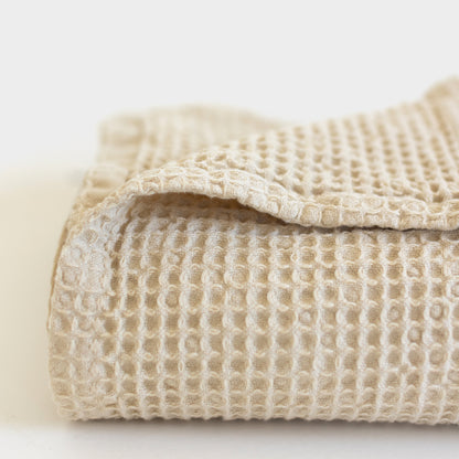 Ivory waffle-weave blanket with textured grid pattern and folded edge detail.