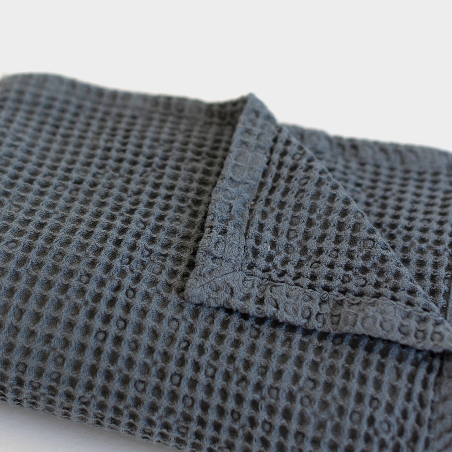 Storm blue waffle blanket with textured grid pattern and folded edge detail.