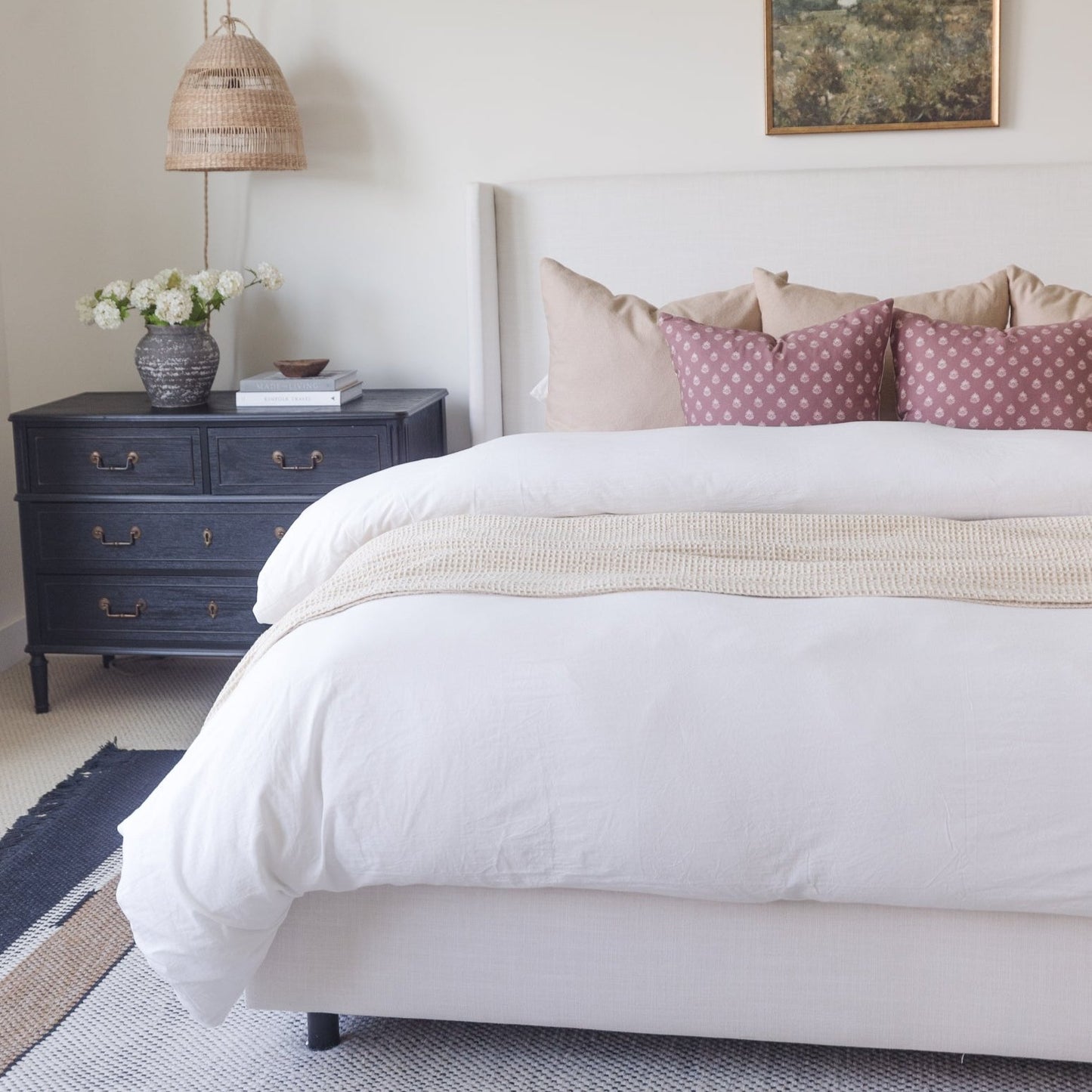 White duvet cover set on king bed with cream pillows and beige throw blanket.