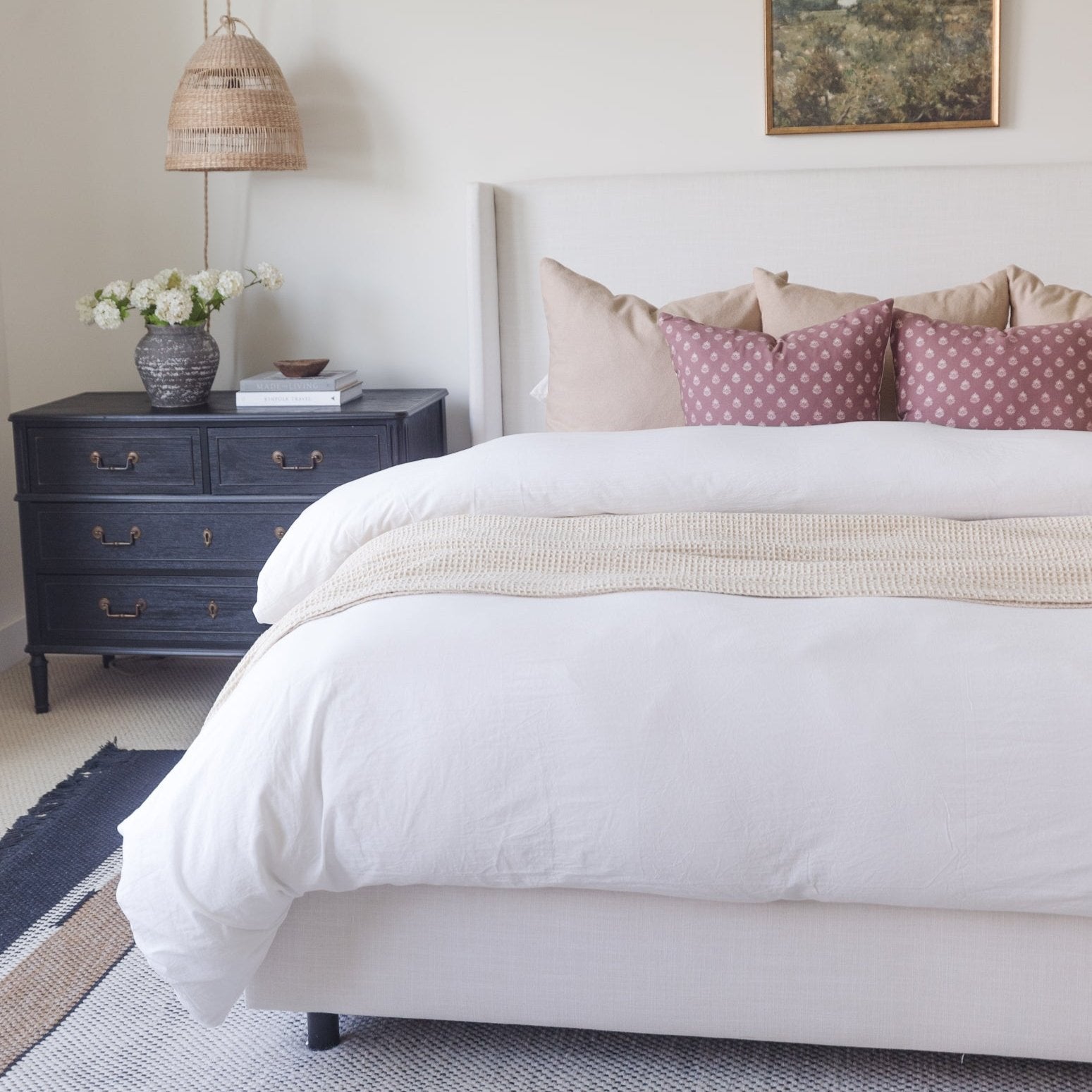 White duvet cover set on king bed with cream pillows and beige throw blanket.
