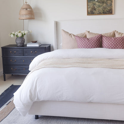 White duvet cover set on king bed with cream pillows and beige throw blanket.