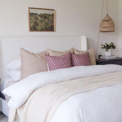 White duvet cover set on king bed with matching pillowcases and textured throw blanket.