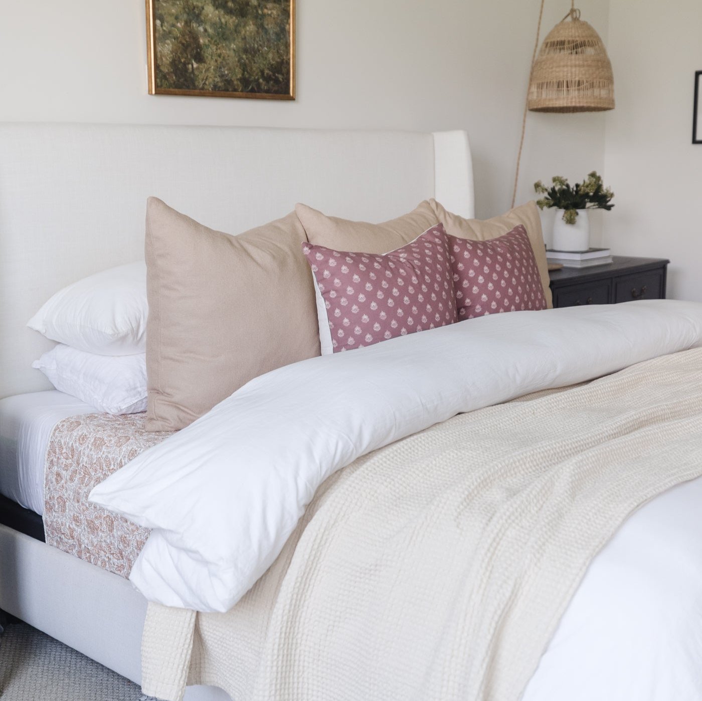 White duvet cover set on king bed with white pillows and decorative cushions.