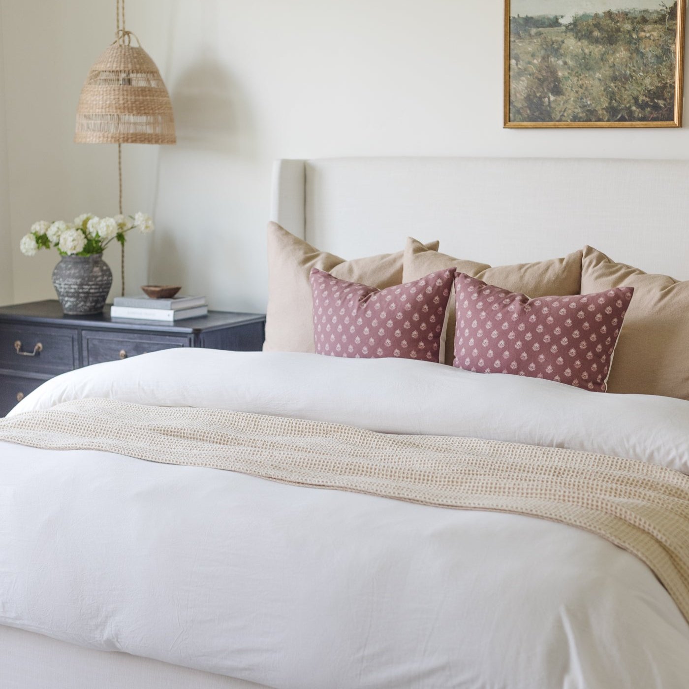White duvet cover set on king-size bed with tan throw and decorative pillows.