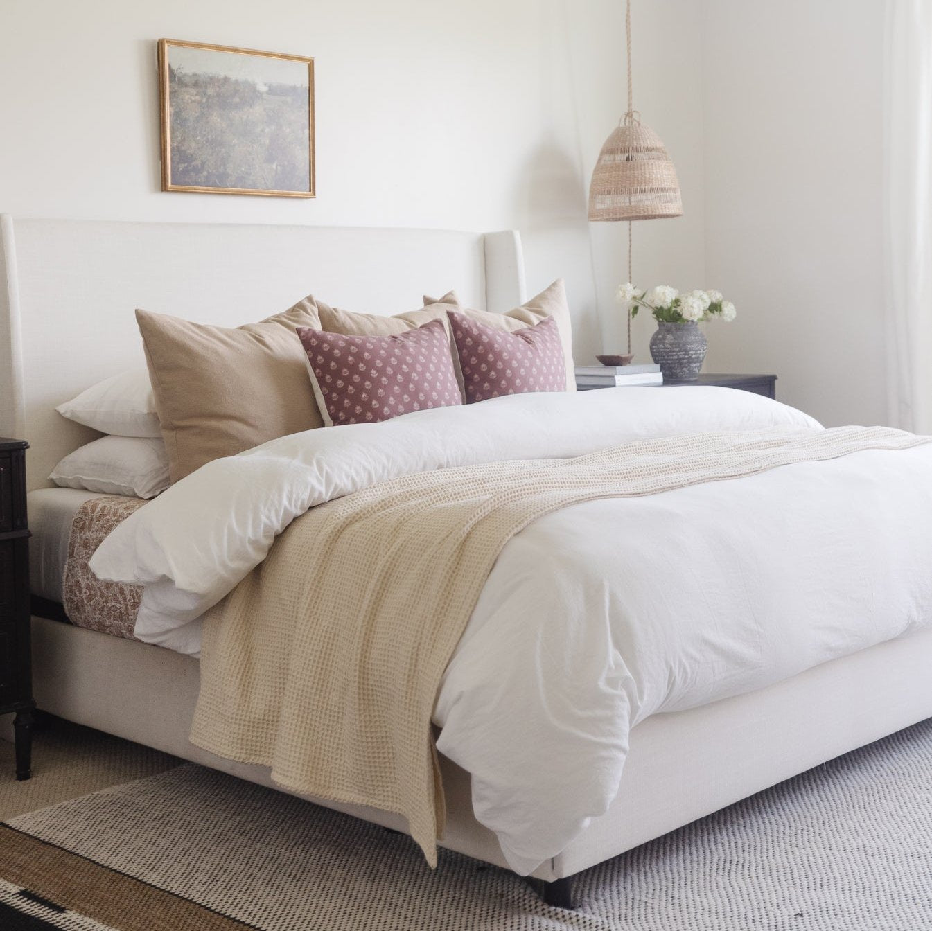 White duvet cover with matching pillowcases on a king bed, styled with decorative pillows and a cream throw blanket.