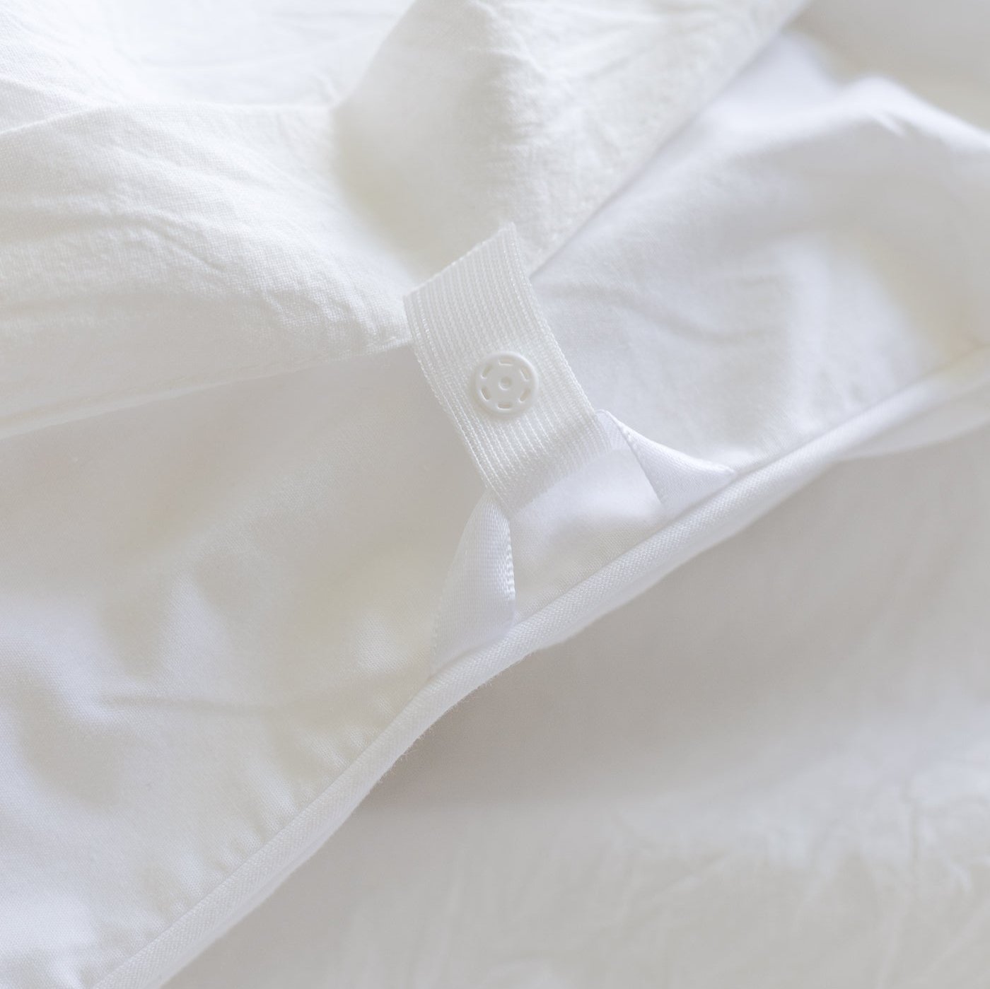 White duvet cover with ribbed fabric tab and button closure detail.