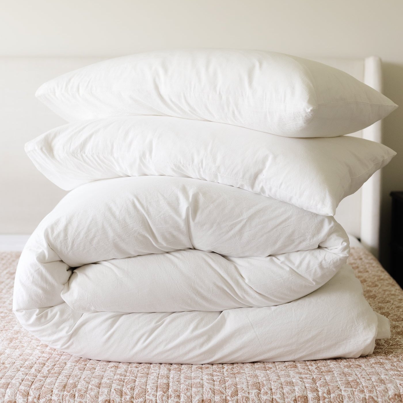 White king duvet cover set folded with matching pillowcases stacked on a bed.