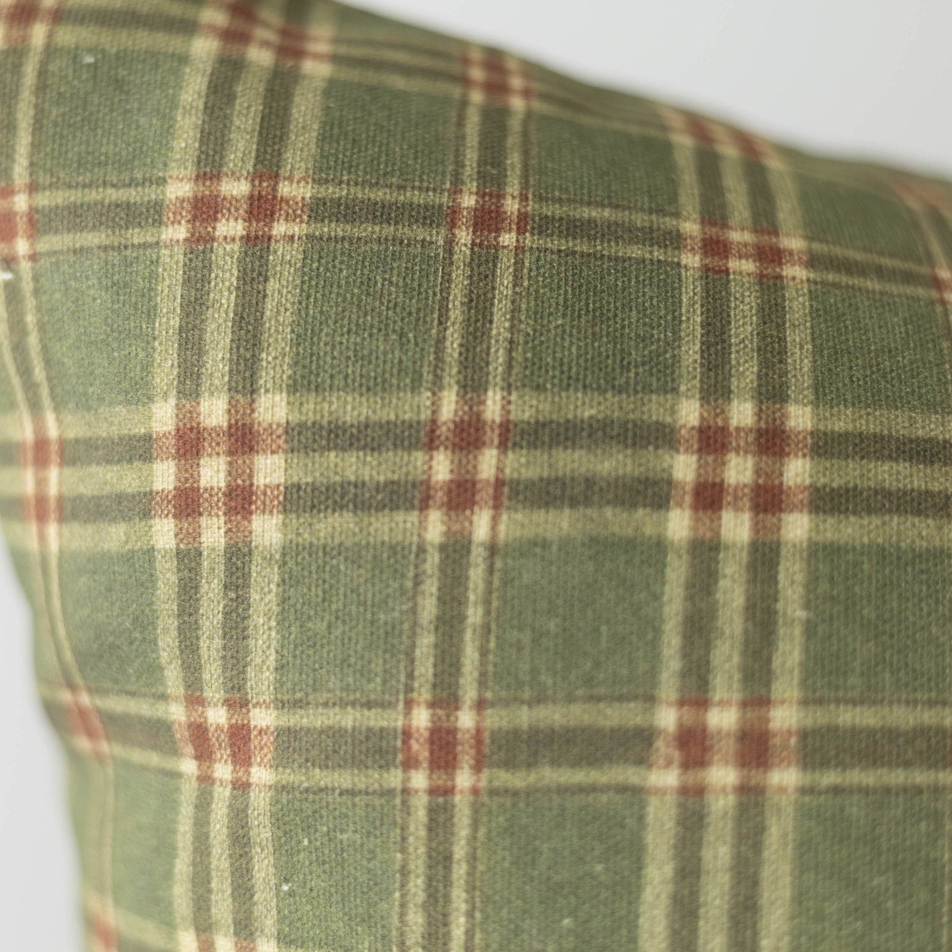 Green plaid fabric with burgundy and cream stripes in a woven tartan pattern.
