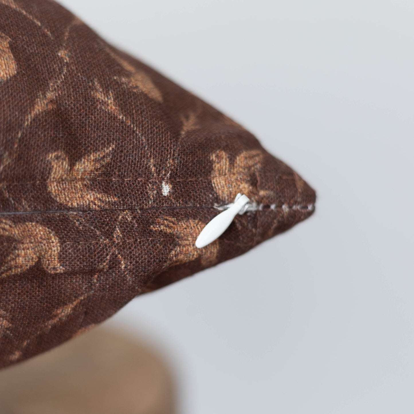 Brown decorative pillow with tan damask pattern and white zipper closure.