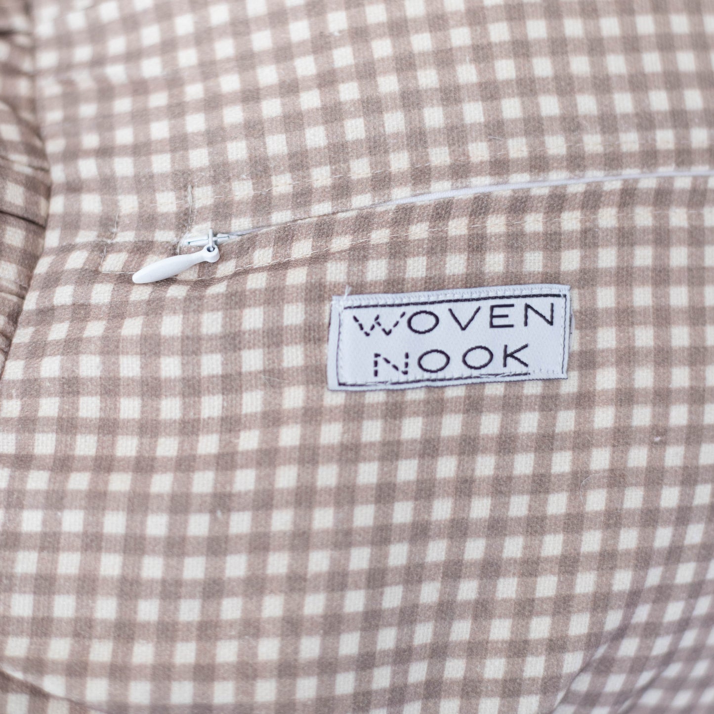 Tan and white mini gingham check fabric with "Woven Nook" brand label and drawstring detail.