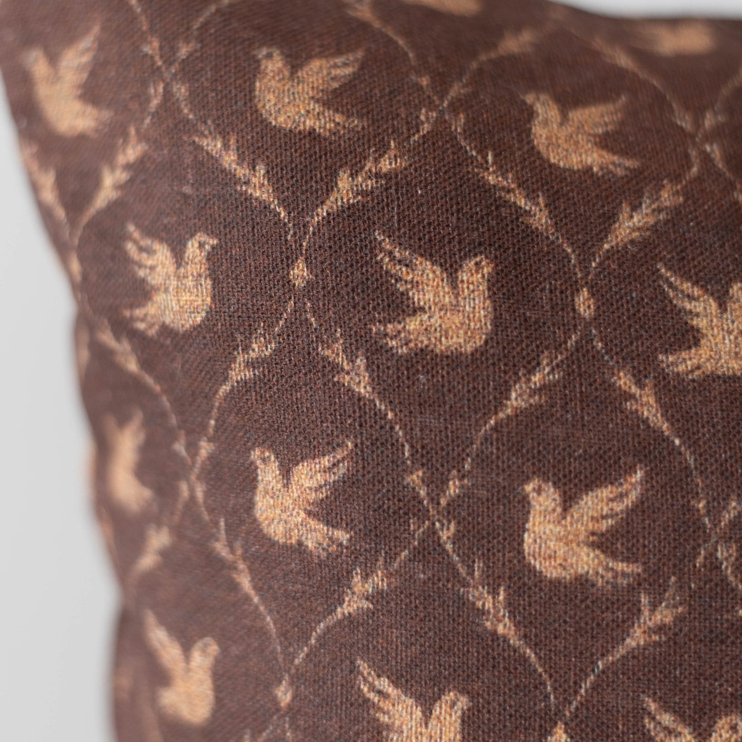 Brown cushion with tan dove silhouettes in a geometric lattice pattern.