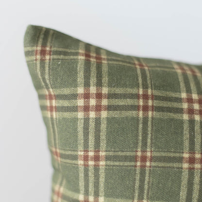 Green plaid pillow with burgundy and cream stripes in tartan pattern.