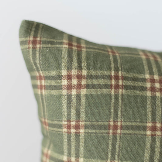 Green plaid pillow with burgundy and cream stripes in tartan pattern.