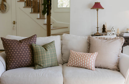 Cream-colored upholstered sofa with four decorative pillows in brown, green, coral, and beige patterns.