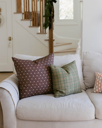 Brown patterned pillow with small repeated motif displayed on cream sofa with coordinating pillows.
