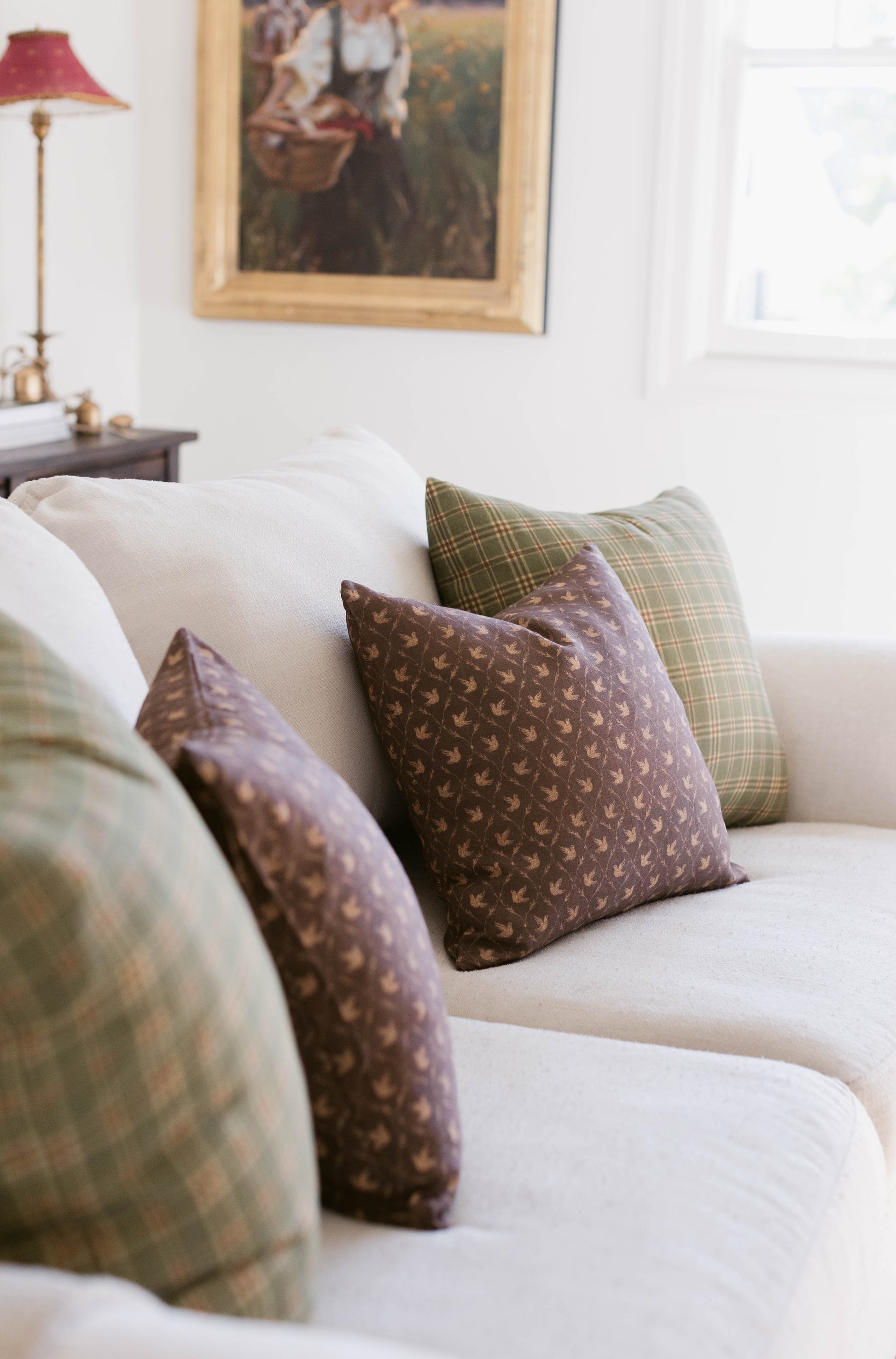 Brown patterned throw pillow with small geometric design displayed on cream upholstered sofa.