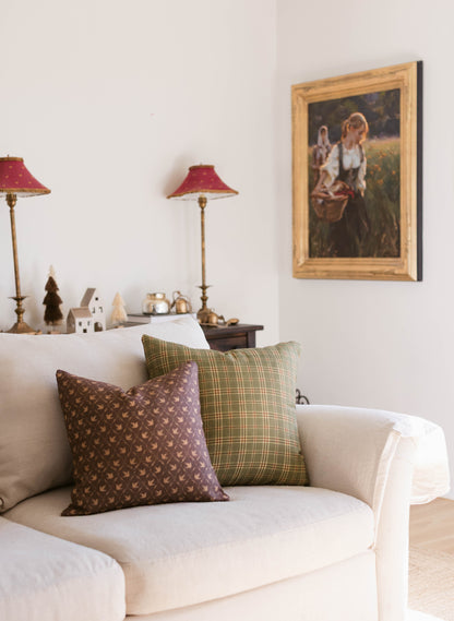 Framed portrait painting with gold wooden frame hanging on white wall above cream upholstered armchair.