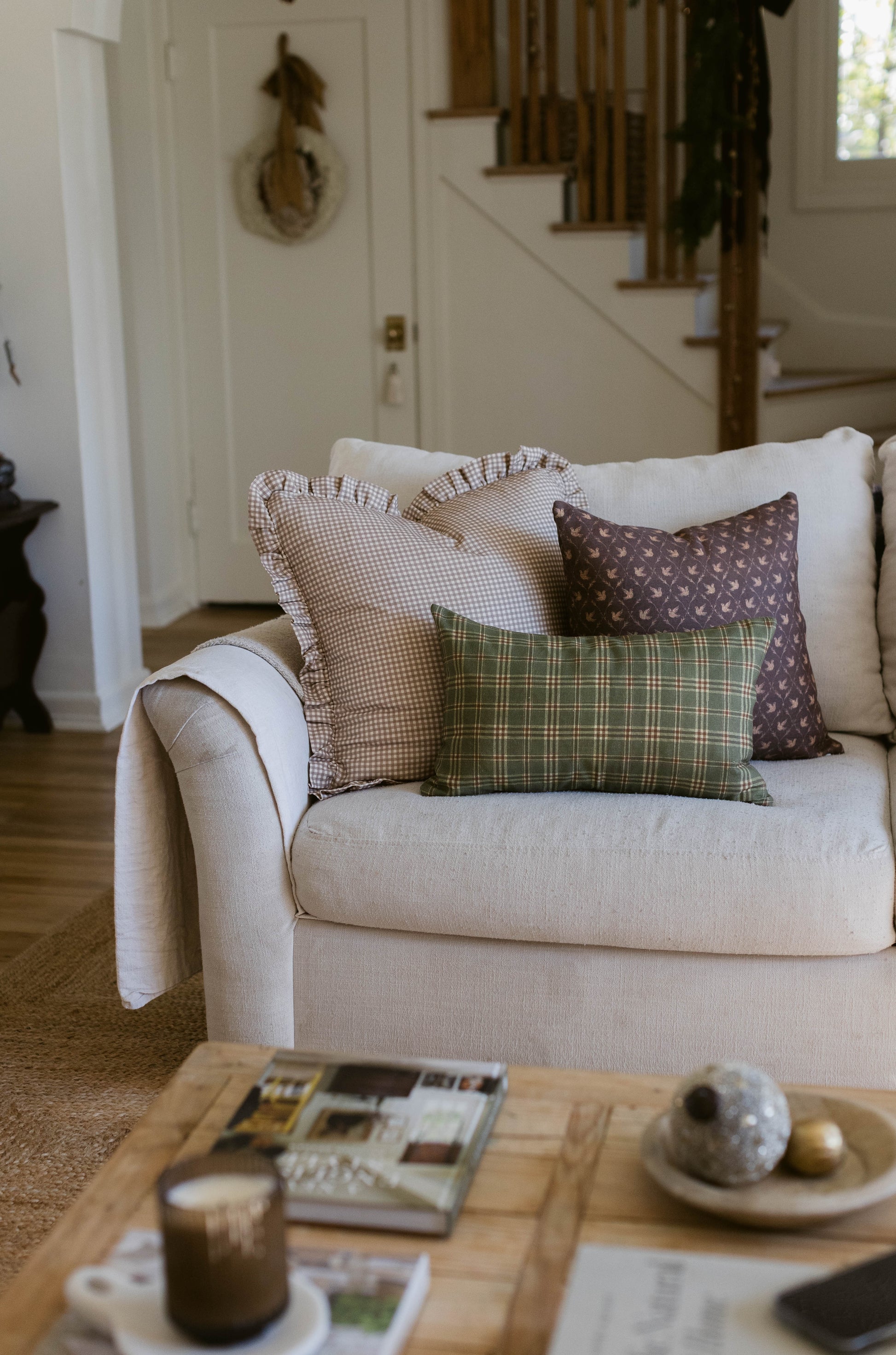 Rectangular pillow with green and cream plaid pattern in 18" x 22" size on cream upholstered chair.