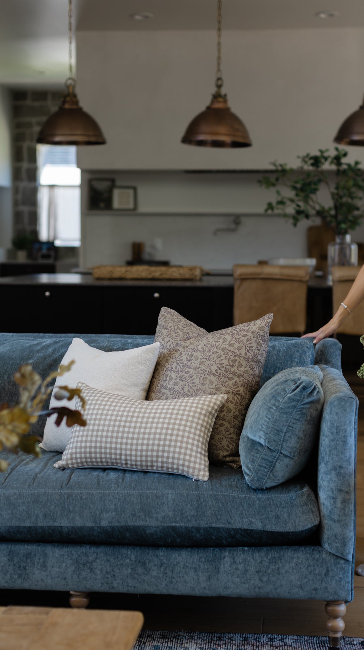 Off-white boucle textured pillow displayed on a blue upholstered sofa with other decorative pillows.
