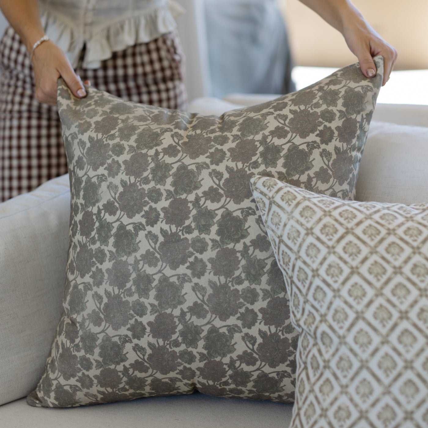 Gray and cream damask floral patterned throw pillow displayed on white sofa.