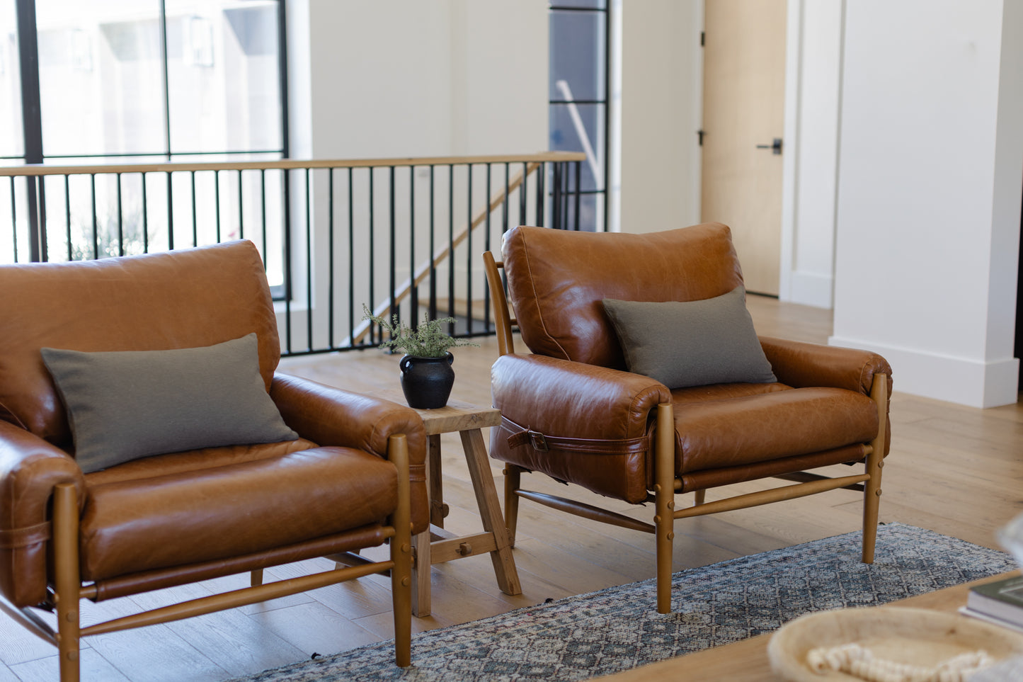 Olive green boucle lumbar pillow displayed on brown leather chair in modern living room setting.