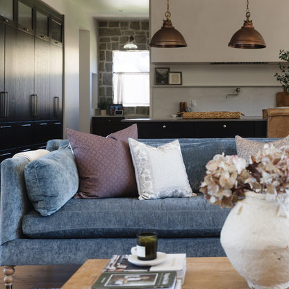 Maroon textured throw pillow displayed on blue sofa with coordinating pillows in living room setting.