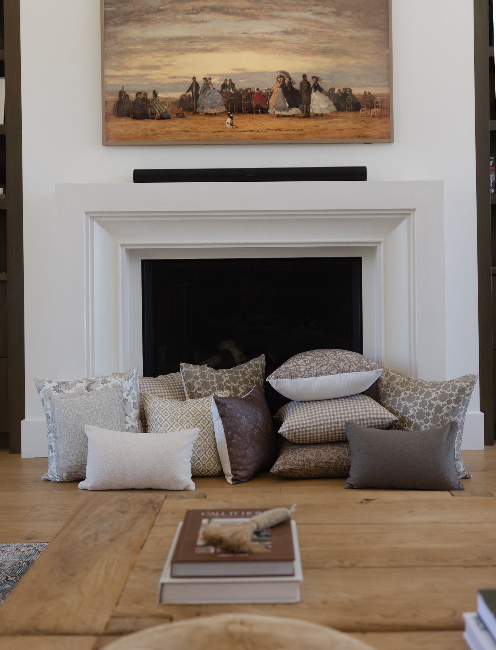 Olive green boucle rectangular pillow displayed among coordinating patterned pillows on fireplace hearth.