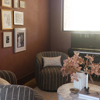 Gallery wall with five framed black and white photographs in gold and silver frames on terracotta wall.